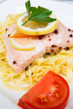 close-up of plate of pasta and smoked salmon with tomatoの写真素材
