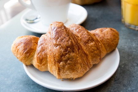 Breakfast with coffee and croissants in a basket on table