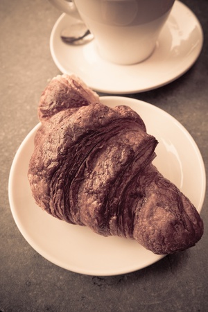 Breakfast with coffee and croissants in a basket on tableの写真素材