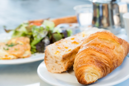 Breakfast with coffee and croissants in a basket on tableの写真素材