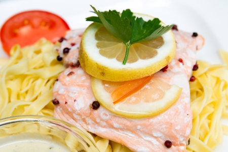 close-up of plate of pasta and smoked salmon with tomatoの写真素材