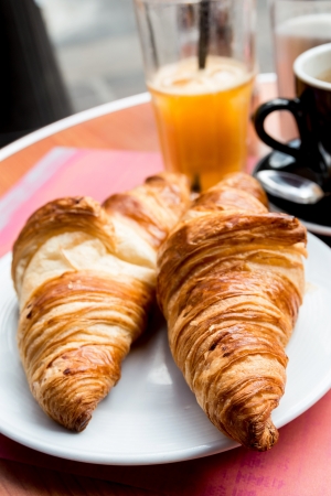 Breakfast with coffee and croissants in a basket on tableの写真素材
