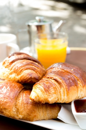 Breakfast with coffee and croissants in a basket on tableの写真素材