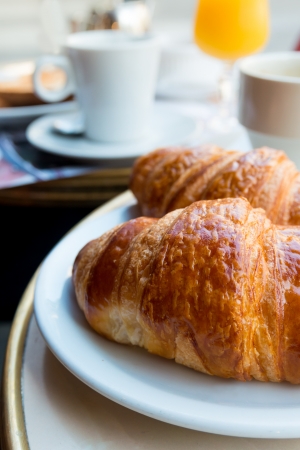 Breakfast with coffee and croissants in a basket on tableの写真素材