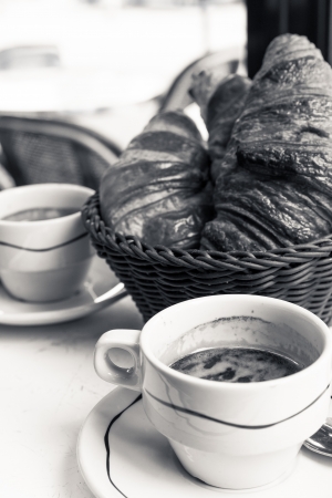 Breakfast with coffee and croissants in a basket on tableの写真素材