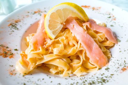 close-up of plate of pasta and smoked salmon with lemonの写真素材