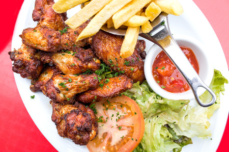 Chicken wings with sauce and golden French fries potatoes の写真素材