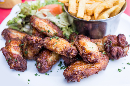 Chicken wings with sauce and golden French fries potatoesの写真素材