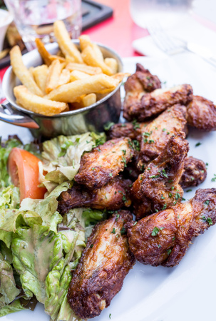 Chicken wings with sauce and golden French fries potatoesの写真素材