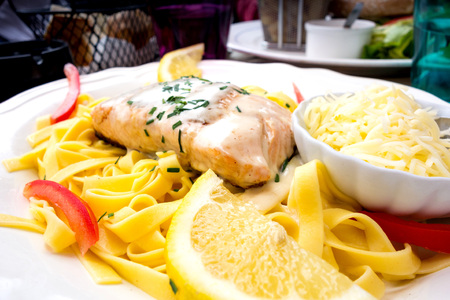 close-up of plate of pasta and smoked salmon with tomatoの写真素材