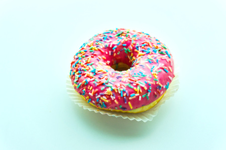 Pink donut with colorful sprinkles isolated on backgroundの写真素材