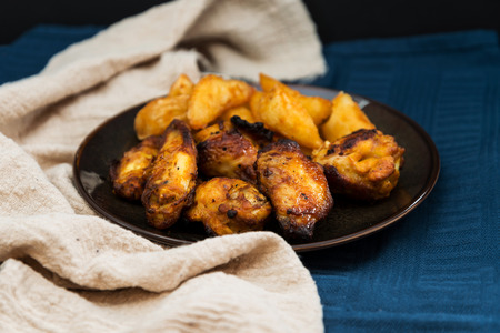 Chicken wings with sauce and golden French fries potatoesの写真素材