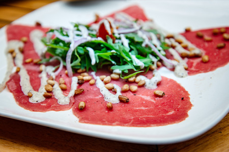 Fresh Sliced raw beef meat with leaf lettuce on the tableの写真素材