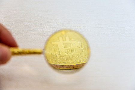 Use a magnifying glass to watch golden bitcoinの写真素材