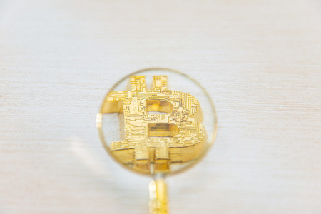 Use a magnifying glass to watch golden bitcoinの写真素材