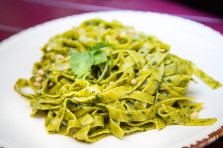 Pasta with pesto sauce and nuts on a the tableの写真素材