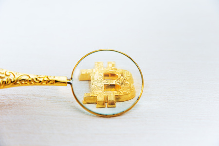 Use a magnifying glass to watch golden bitcoinの写真素材