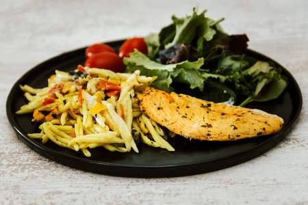 close-up of plate of pasta and chicken with lettuceの写真素材