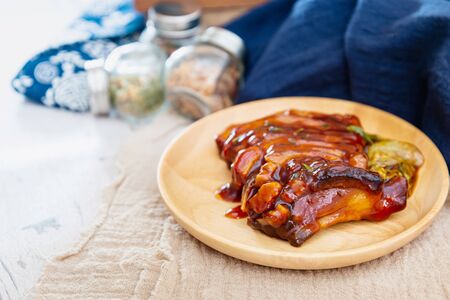 Chinese lacquered pork slices with its caramelized sauce prepared for eating in a wooden plateの写真素材