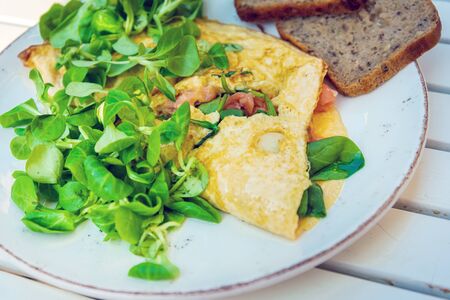 Tasty homemade omelette with fresh salmon served with lettuce on top in white ceramic vintage plateの写真素材