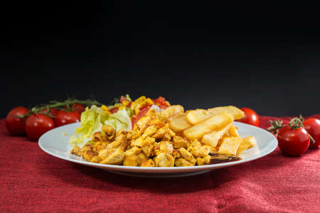 Traditional greek Kebab meat in sandwich prepared with pita bread, cheese and fresh tomatoes and lettuce served in wooden plate with fried potatoes slices.の写真素材