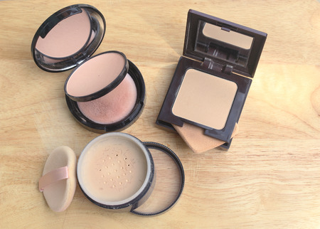press powder and loose powder on wooden background