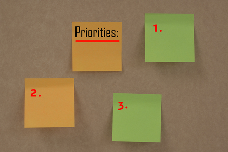 Sticky Notes with word "priorities" on brown wallの写真素材