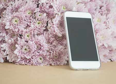 mobile phone with pink flowers background. selective focusの写真素材