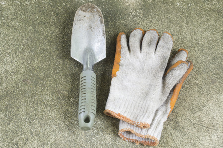 dirty garden shovel and gloves on concrete floorの写真素材