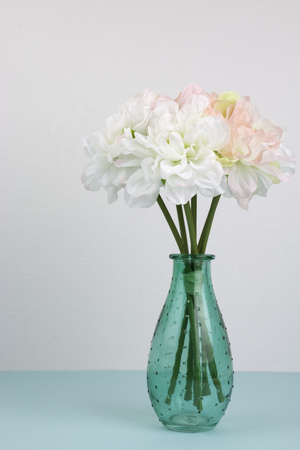 Beautiful flowers in a green vase on blue paper.の写真素材