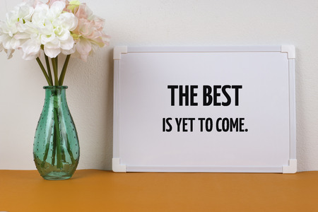 Inspirational quote "The best is yet to come" on flower vase and white board background.の写真素材