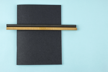 Black notebook and pencils on blue background.の写真素材