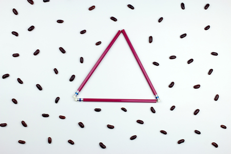 red pencils triangle frame with red beans on white background. top view.の写真素材