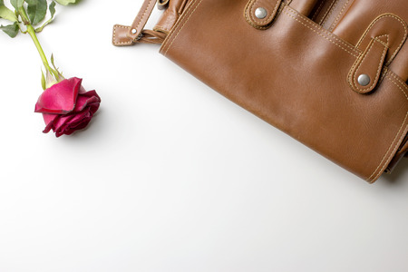 brown leather bag with rose on white table background. top view. ?at lay.の写真素材