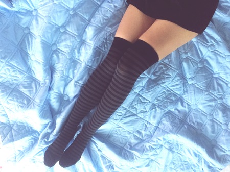 Woman legs wearing cozy socks on the bed. Top view.の写真素材