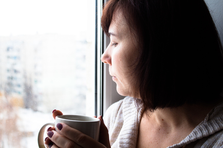 A woman sitting near window with cupの写真素材