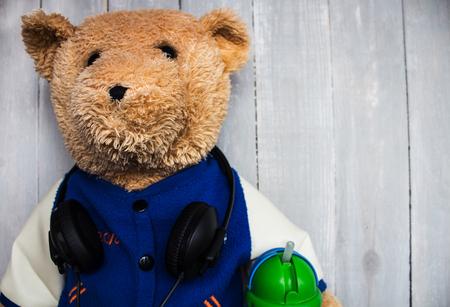 a teddy bear with headphones on wooden backgroundの写真素材