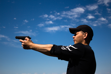 man holding gun in hands sky backgroundの写真素材