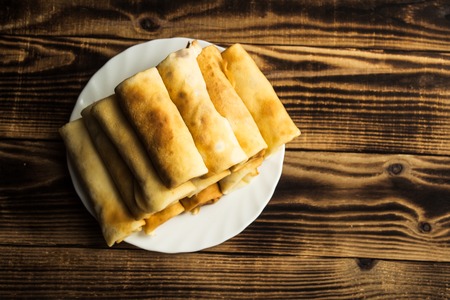 stuffed crepe stacked on white plate wooden backgroundの写真素材