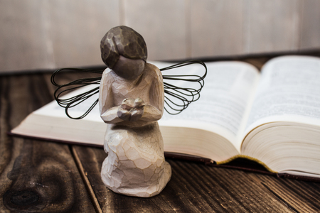 an angel and bible on wooden backgroundの写真素材