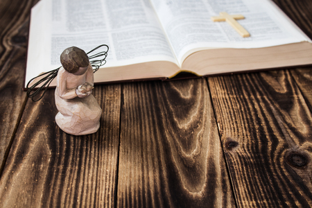 an angel and bible on wooden backgroundの写真素材