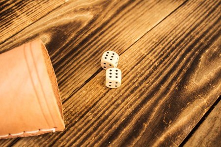 wood dice on wooden background on six with leather cup