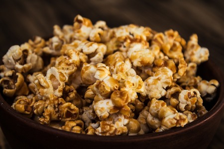 caramel popcorn in clay bowl on wooden backgroundの写真素材