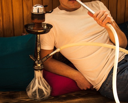 man is sitting and smoking a hookahの写真素材