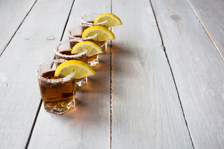alcohol shot drinks with lemon and salt on wooden background