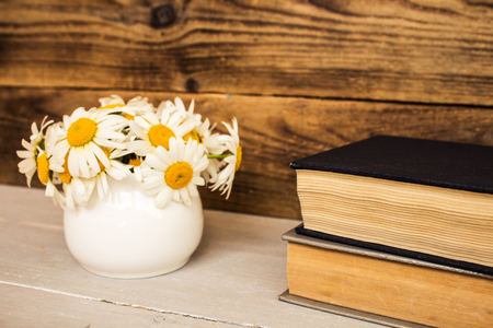 bouquet of white daisies and books on wooden backgroundの写真素材
