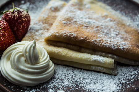 Pancakes crepe with strawberries and powdered sugar