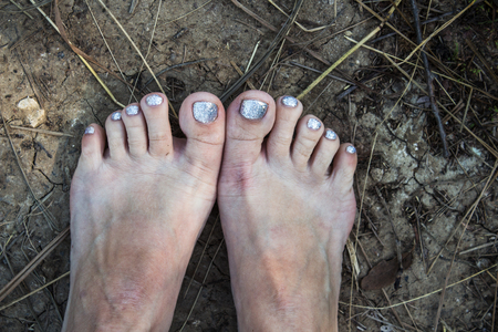 feet of a woman with a pedicure on the ground summerの写真素材