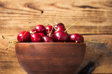 bowl of ripe red cherries summer wooden backgroundの写真素材