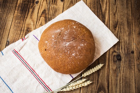 a bread and spikelets of wheat on wooden backgroundの写真素材